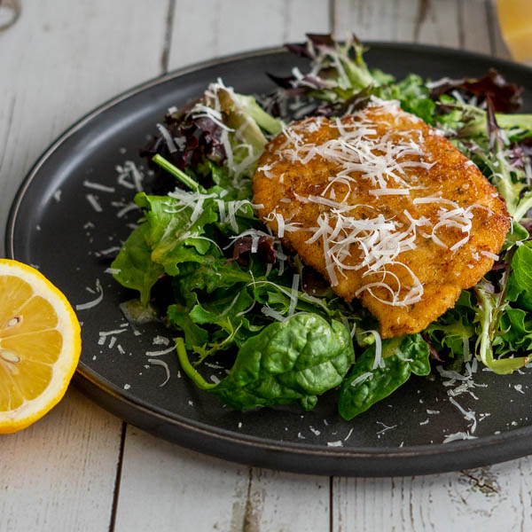 Breaded chicken over spring salad mix with lemon and parmesan