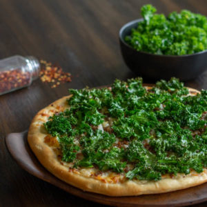 Pizza with white sauce, kale and sausage