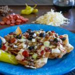 Pasta Chips Topped with Cheese, Pepperoni, Sausage, Black Olives and Green Onions on a Blue Plate