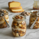 Three parfaits with a spoons, pound cake, caramel and pecans.