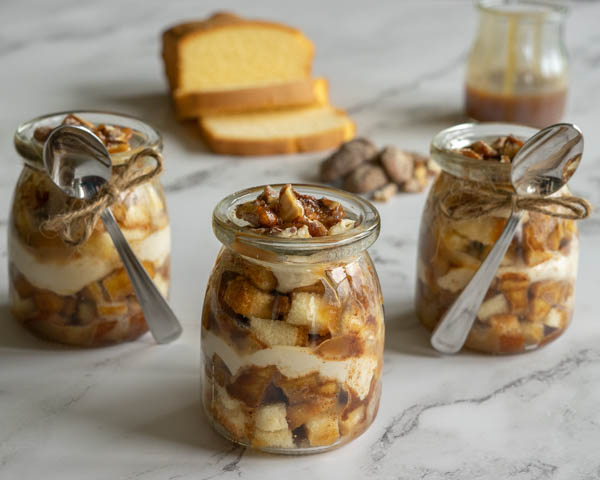 Three parfaits with a spoons, pound cake, caramel and pecans.