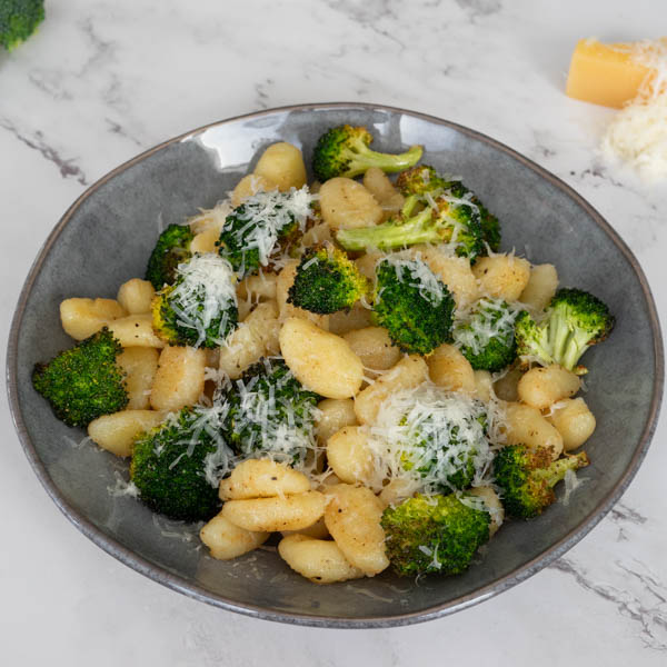 Brown Butter Gnocchi with broccoli, and parmesan in a grey bowl.