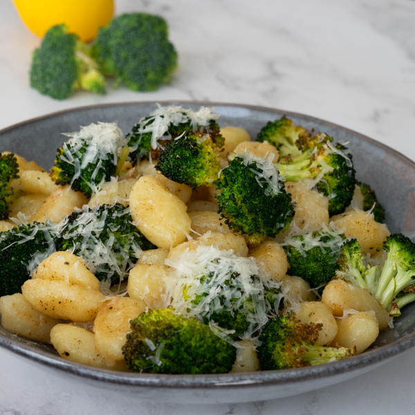 Brown Butter Gnocchi with broccoli, and parmesan in a grey bowl.