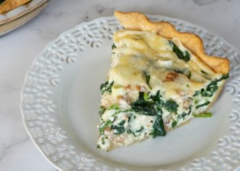 Spinach and Bacon Quiche in a glass pie dish.